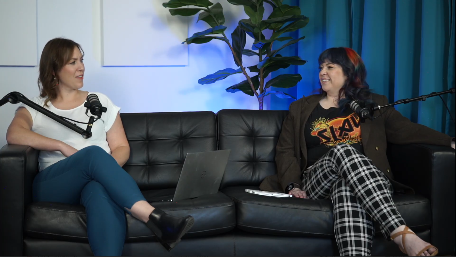 Nora and Bethany doing their Interocept podcast on our teal set with black leather couch and blue back lighting.