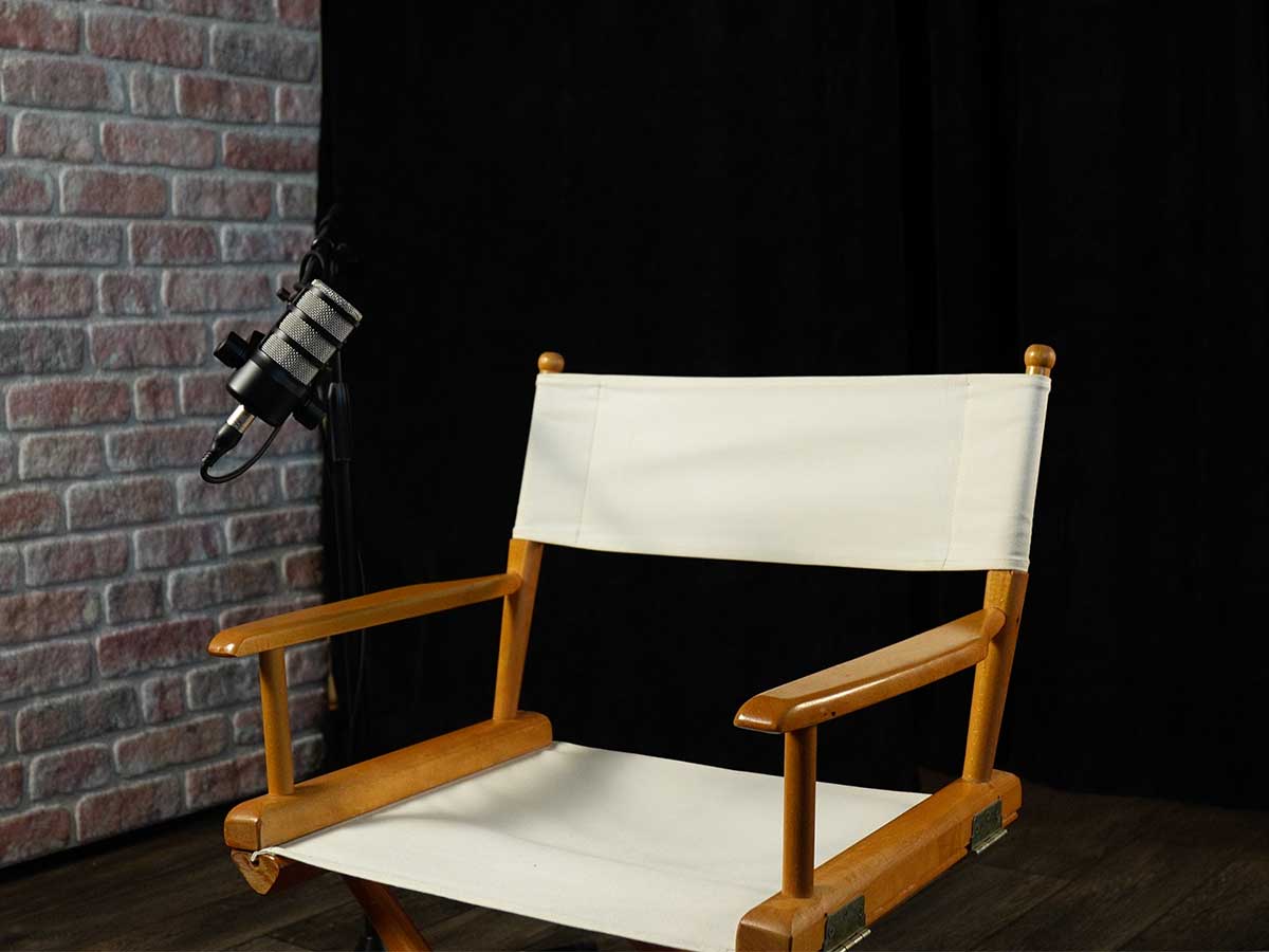Empty solo directors chair set with brick background and black curtains