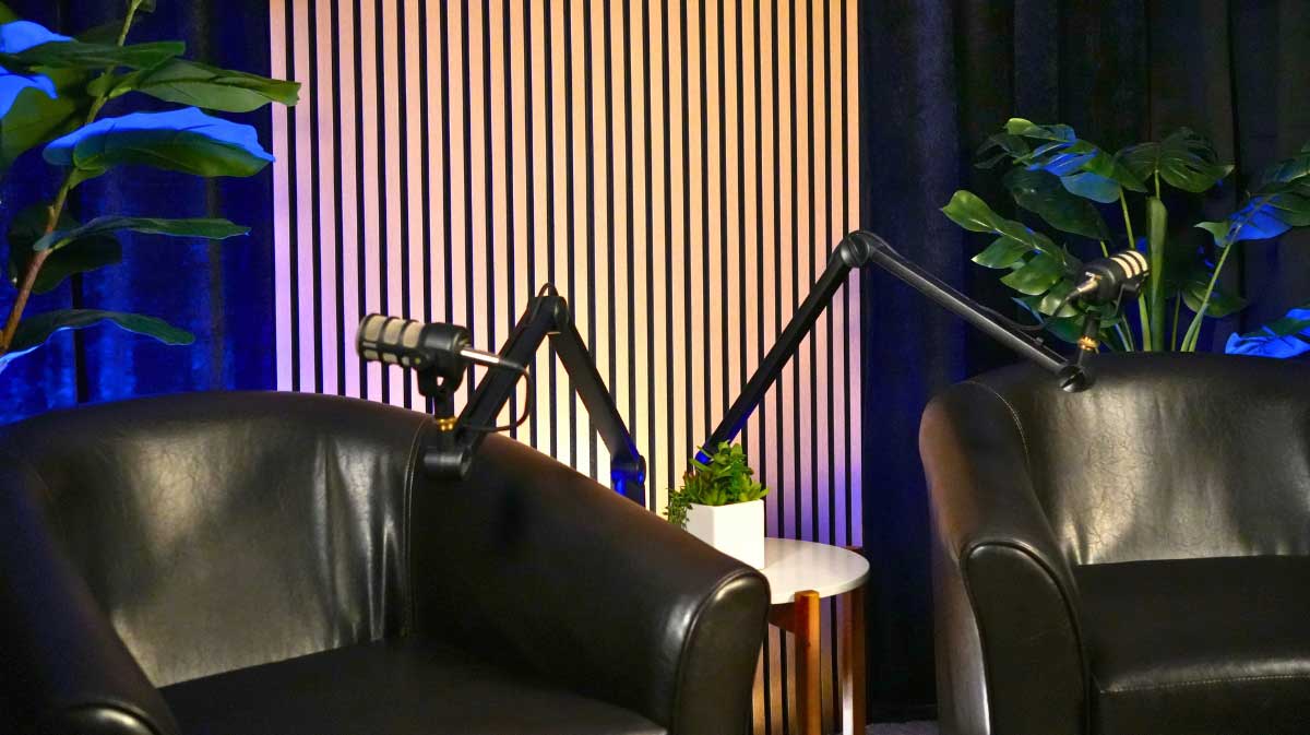 Empty two person set with dual dark leather chairs slatted wall with black curtains and blue backlighting..