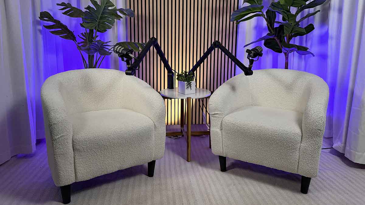 Empty white set with dual white chairs slatted wall with white curtains and light purple backlighting.